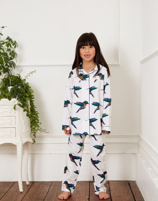 Child model wears kids cotton, shirt and trouser, white base with repeating hummingbird pattern, blue piping