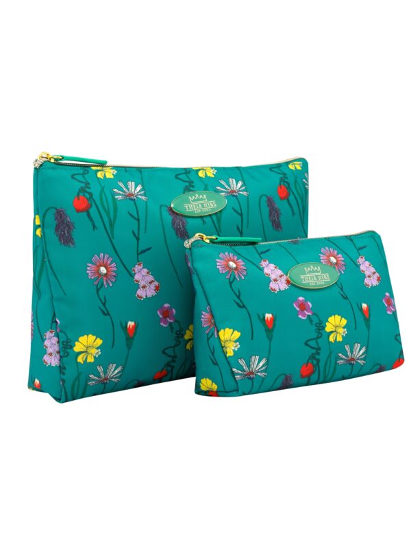 Angled shot of synthetic deep green cosmetic bag set, one larger bag and one smaller, Their Nibs badge in centre, repeating floral pattern