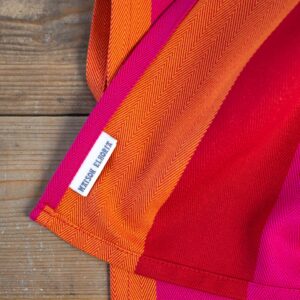 Red-orange-pink-tea-towels-corner-with-label-showing-on-wooden-table