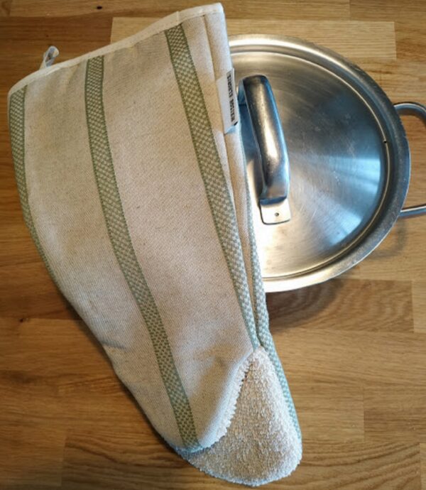 Long oven glove gauntlet style over a cooking pot on a wooden work surface