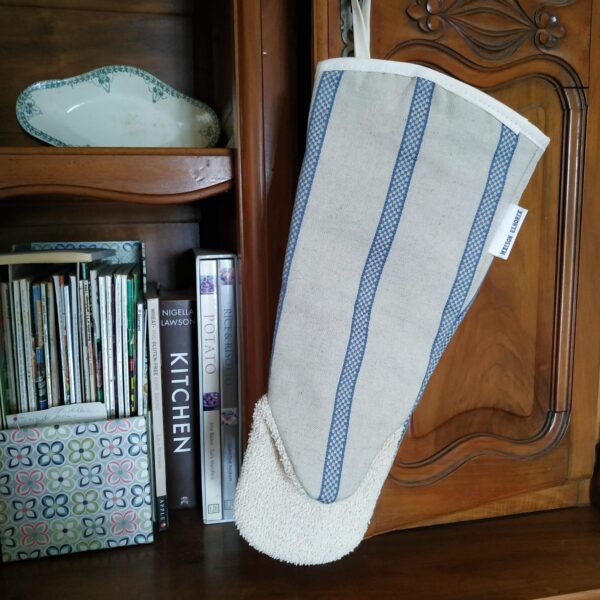 Long gauntlet oven glove with blue stripes hanging off an old kitchen dresser door with cooking books