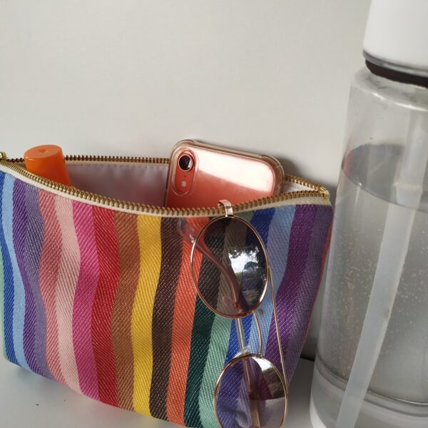 rainbow wash bag with a water bottle and sunglasses hanging of it