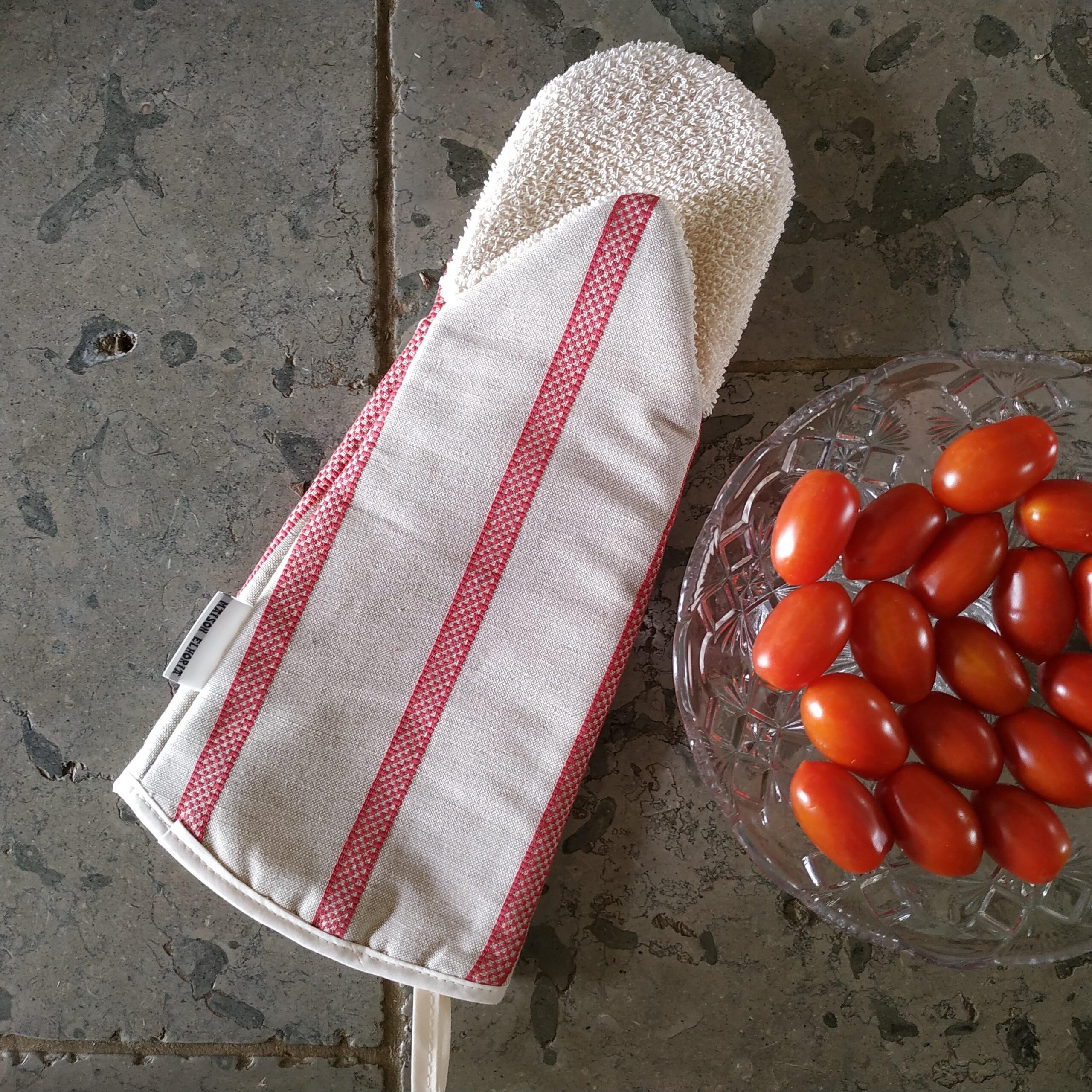 Red stripes gauntlet oven glove on grey stone with a bowl of cherry tomatoes