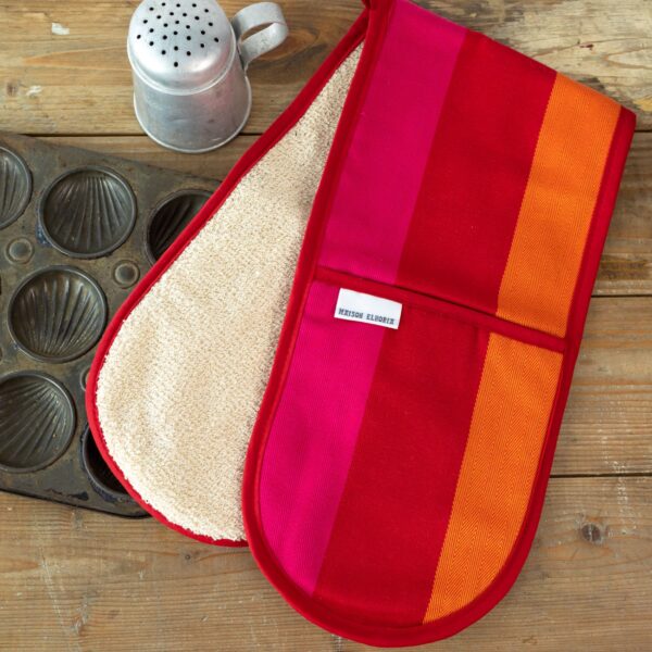 red orange pink double oven gloves on wooden table with baking accessories