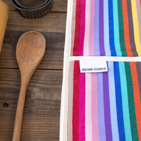 close up of a Double oven glove rainbow with wooden spoon on wooden table