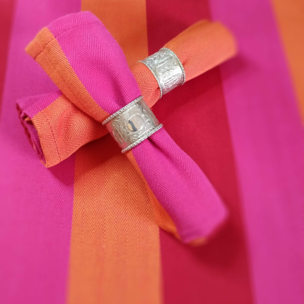 red orange pink napkins rolled in silver rings, on a red orange pink tablecloth